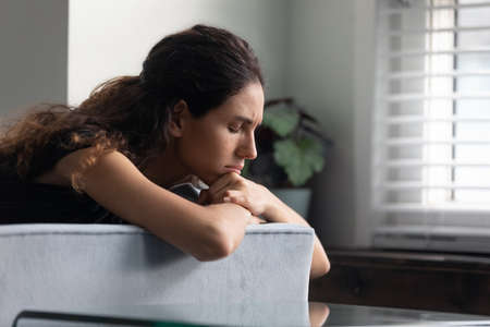 Close up upset thoughtful woman with closed eyes lying on couch alone, lost in thoughts, thinking...