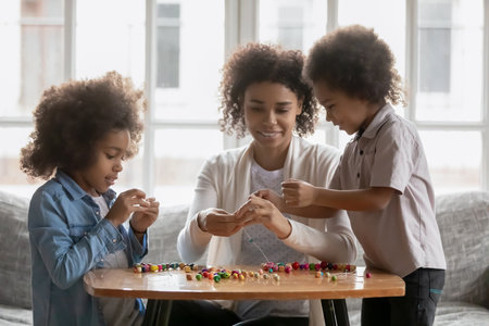 Millennial mom teaching kids to make craft decoration. Mom and children sharing creative activity,...