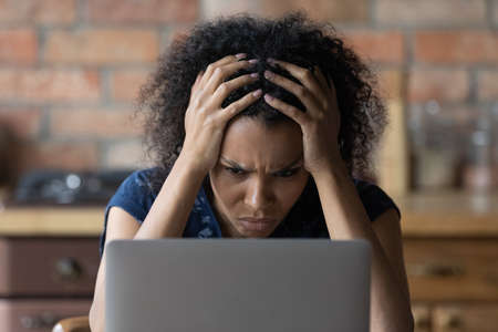Unexpected problem. Angry nervous young afro american female scratch head stare at laptop feel panic...