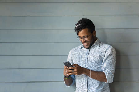 Digital generation. Confident african hipster guy use smartphone chat at social network in good...