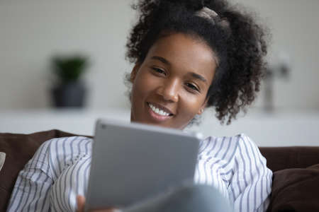 Close up of smiling biracial woman use tablet talk speak on video call on gadget at home. Happy...