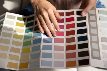 Young lady interior graphic designer illustrator think on project hold palette of various colored samples in hands. Woman client customer choose example of colors before apartment remodeling. Close upの写真素材