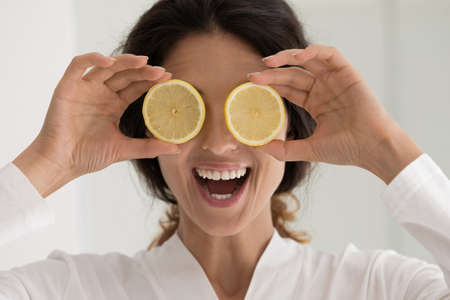 Close up overjoyed woman holding fresh lemon slices, recommending natural beauty products or spa procedures, skincare or dentistry, happy young female in bathrobe excited by organic treatmentの写真素材