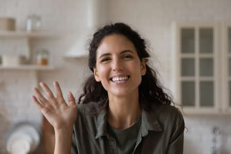 Head shot portrait of excited smiling woman waving hand, making video call, greeting friends or relatives, happy young female blogger influencer recording vlog, involved in internet meetingの写真素材