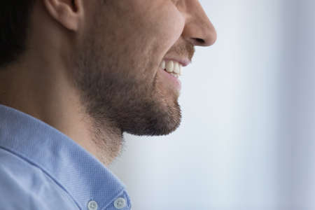 Close up crop side view of young Caucasian man smile show healthy white even teeth after good dental treatment. Happy male feel optimistic positive isolated on gray background. Dentistry concept.の写真素材