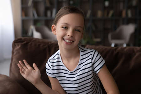 Profile picture of smiling little teen girl child wave greet at camera have digital webcam virtual...