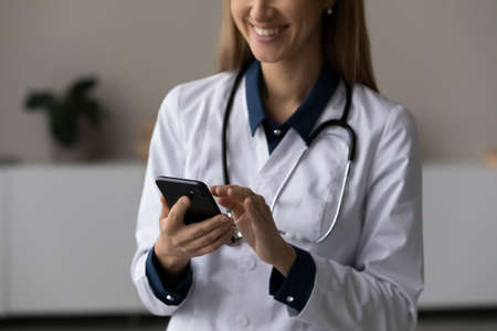 Close up of smiling female doctor in white medical uniform consult client patient online on video...