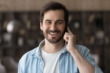 Head shot portrait smiling man talking on phone, having fun, enjoying pleasant conversation with friend or girlfriend, hearing good news, satisfied customer excited by good connection qualityの写真素材