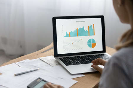 Analyzing data. Close up over shoulder view of young businesswoman preparing financial report...