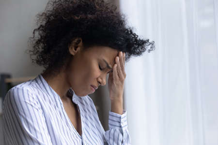 Unhappy young African American woman feel depressed sad crying alone at home. Upset millennial mixed race female distressed with bad negative news, suffer from problems misfortune or failure.の写真素材