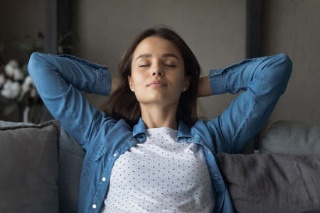 Head shot happy relaxed attractive young woman sleeping on cozy sofa, breathing fresh air, napping...