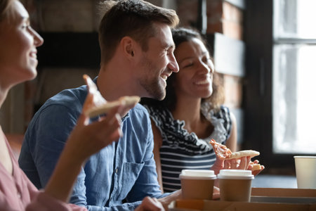 Happy young caucasian man enjoying spending carefree leisure weekend time in cafe with mixed race...