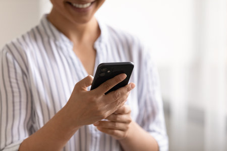 Crop close up of Indian woman hold use modern cellphone talk speak on video call on gadget online. Mixed race female look at smartphone screen text or browse internet on device. Technology concept.の写真素材