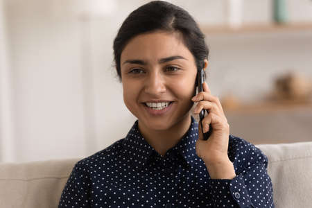 Smiling young Indian woman use modern cellphone talk speak on gadget with good mobile provider...
