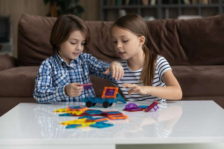 Cute little Caucasian boy and girl children have fun play with blocks brocks at home together. Smiling small brother and sister kids feel playful engaged in game activity on weekend. Hobby concept.の写真素材