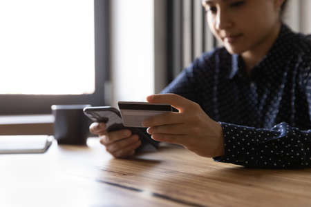 Female Indian client using with smartphone mobile bank service app and credit card for online...