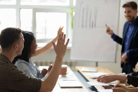 Audience raising hands up for asking question to presenter on office meeting in boardroom. Business leader, coach, mentor giving training, answering to engaged students, interns, employeesの写真素材