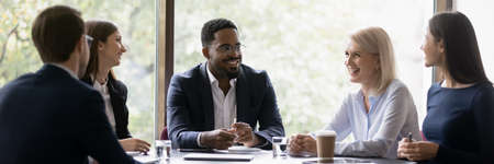 Happy diverse different aged business team discussing work. Leader and employees talking in office...
