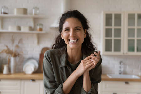 Headshot portrait of cheerful millennial latin woman professional trainer coach give master class webinar from home kitchen use webcam. Happy confident young lady presenter talk on camera record vlogの写真素材
