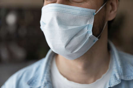 Close up young man wearing medical disposable facemask, suffering from air pollution or preventing spreading coronavirus covid19 infection, world pandemic outbreak, healthcare quarantine lifestyle.の写真素材