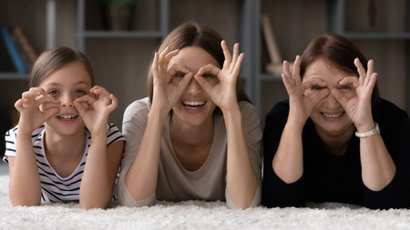 Happy daughter girl, mom, grandma having fun at home together, enjoying leisure on comfortable...