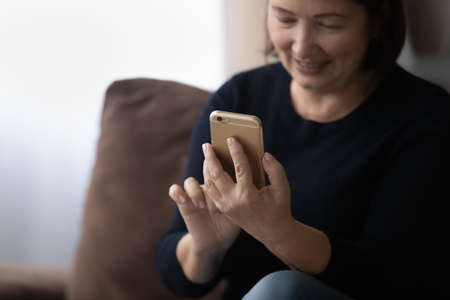 Happy older 60s woman using telehealth app on mobile phone, making appointment with doctor. Mature...