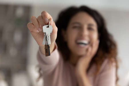 Crop close up of smiling Latino woman show keys to new house or apartment feel excited moving in or relocating. Hispanic female renter celebrate relocation to own home. Rental, rent concept.の写真素材