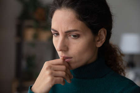 Close up thoughtful upset woman thinking about personal or relationships problems alone, biting nail, frustrated depressed young female lost in thoughts, feeling lonely and sad, ponderingの写真素材