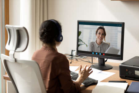 Back view of young Indian businesswoman look at PC screen have webcam digital virtual event with...