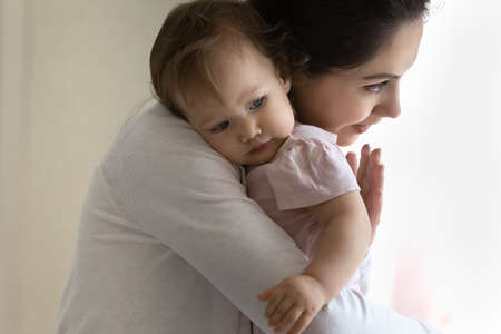 Loving happy young Caucasian mother hug cuddle cute little baby daughter enjoy time at home...