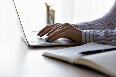 Crop close up of Caucasian businesswoman sit at desk at home office type on laptop keyboard consult...