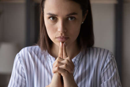 Portrait of determined serious young Caucasian businesswoman look at camera thinking making decision. Concentrated millennial woman leader make hand gesture pondering or planning. Leadership concept.の写真素材