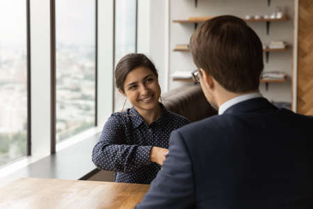 Multiracial businesspeople make profit deal shake hands finish successful negotiations in modern company office. Employer congratulate Indian female applicant with get new job. Human resources conceptの写真素材
