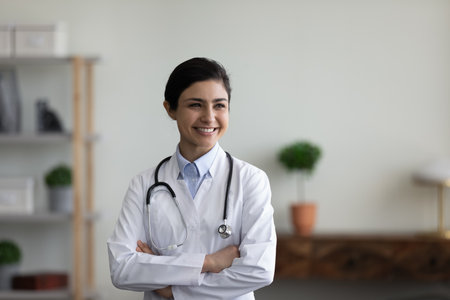 Confident happy young female indian ethnic female doctor general practitioner in white medical...