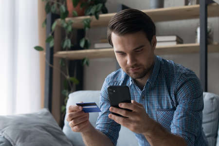 Serious customer making payment by credit cards, paying orders, purchases on internet store...