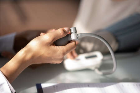 Hand of doctor using sphygmomanometer for checking blood pressure. Physician examining patient with...