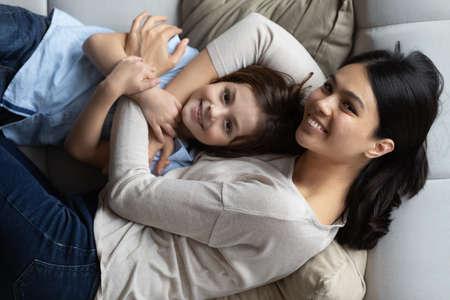 Above top view affectionate millennial korean asian woman cuddling little cute kid son, lying...