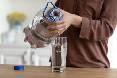 Refreshment. Closeup of young woman hands hold plastic bottle with fresh still purified clear...
