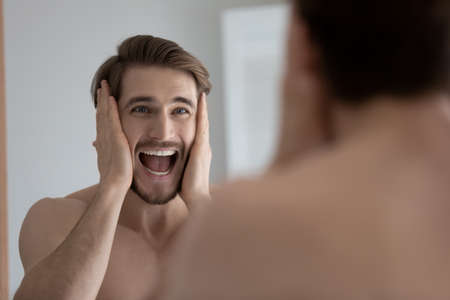 35s man shout looks in mirror touches his head open mouth feels stressed due facial rough, rash,...