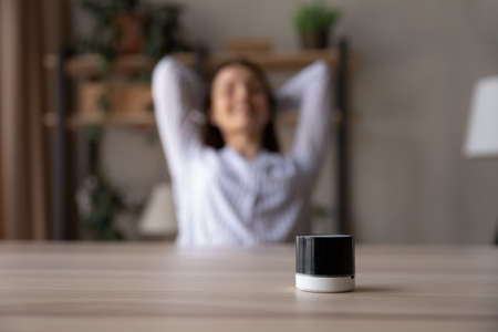 Close up portable speaker on relaxed young woman table, carefree female resting leaning back in comfortable chair, enjoying favorite music, wireless equipment for sound and digital assistantの写真素材