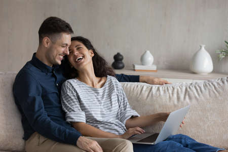 Happy loving young family couple resting using computer software applications, buying goods on...
