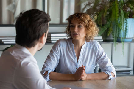 Two business coworkers, partners negotiating on project, deal. Serious recruit HR manager, employer interviewing job candidate on meeting in office. Female boss, leader instructing employeeの写真素材