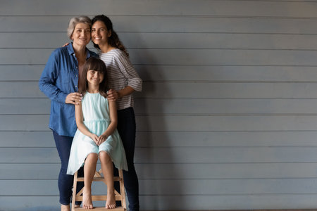Happy family related women and kid hugging with love, care, support, standing together, posing at...