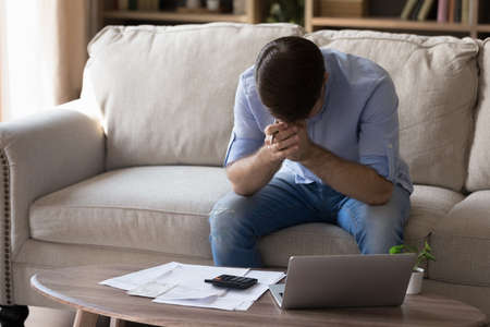 Unhappy young man calculating domestic budget, feeling nervous having lack of money, getting bank...