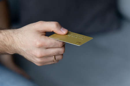 Close up young man holding plastic credit card in hand, buying goods with wireless payment service,...