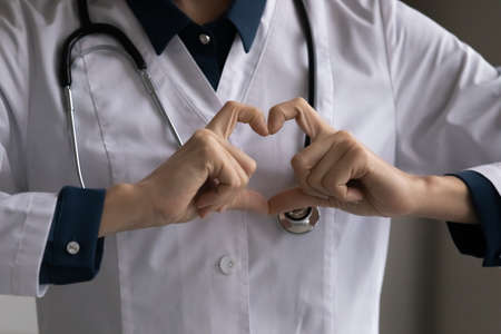 Close up cropped of female doctor cardiologist showing heart gesture, expressing support and care, woman professional practitioner gp recommending regular medical checkup, healthcare conceptの写真素材