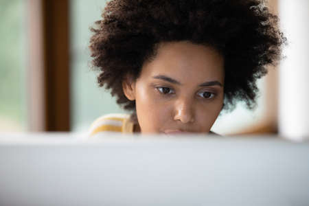 Serious Black student girl working on study research at computer. Thoughtful young female employee,...