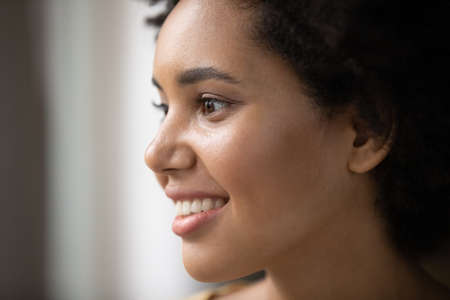 Happy beautiful young African American woman face portrait. Thoughtful 20s girl with perfect skin, no makeup, looking away, thinking, smiling. Beauty care, skincare, youth conceptの写真素材