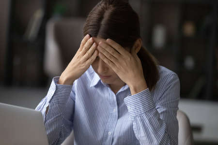 Frustrated sad woman sit at desk near laptop feel tired or worried about problems, troubled with...