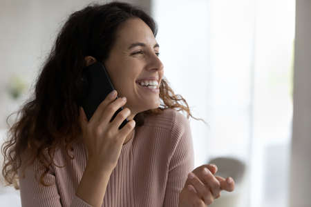 Head shot close up laughing woman chatting on cellphone, enjoying pleasant conversation, beautiful smiling female holding smartphone, talking with friend or boyfriend, making or answering phone callの写真素材